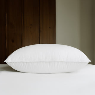 Tencel Organic Cotton White Goose Down Pillow on bed near wooden door.