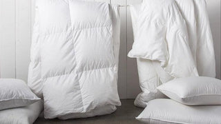 White comforter, pillows, and blankets displayed on a clothesline, accompanying a duvet quiz to determine the best fit for you.