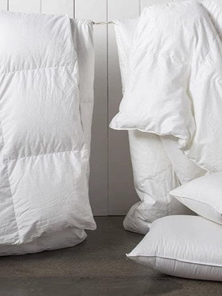  A white comforter, pillows, and blankets hanging on a clothesline, illustrating a duvet quiz for personalized selection.